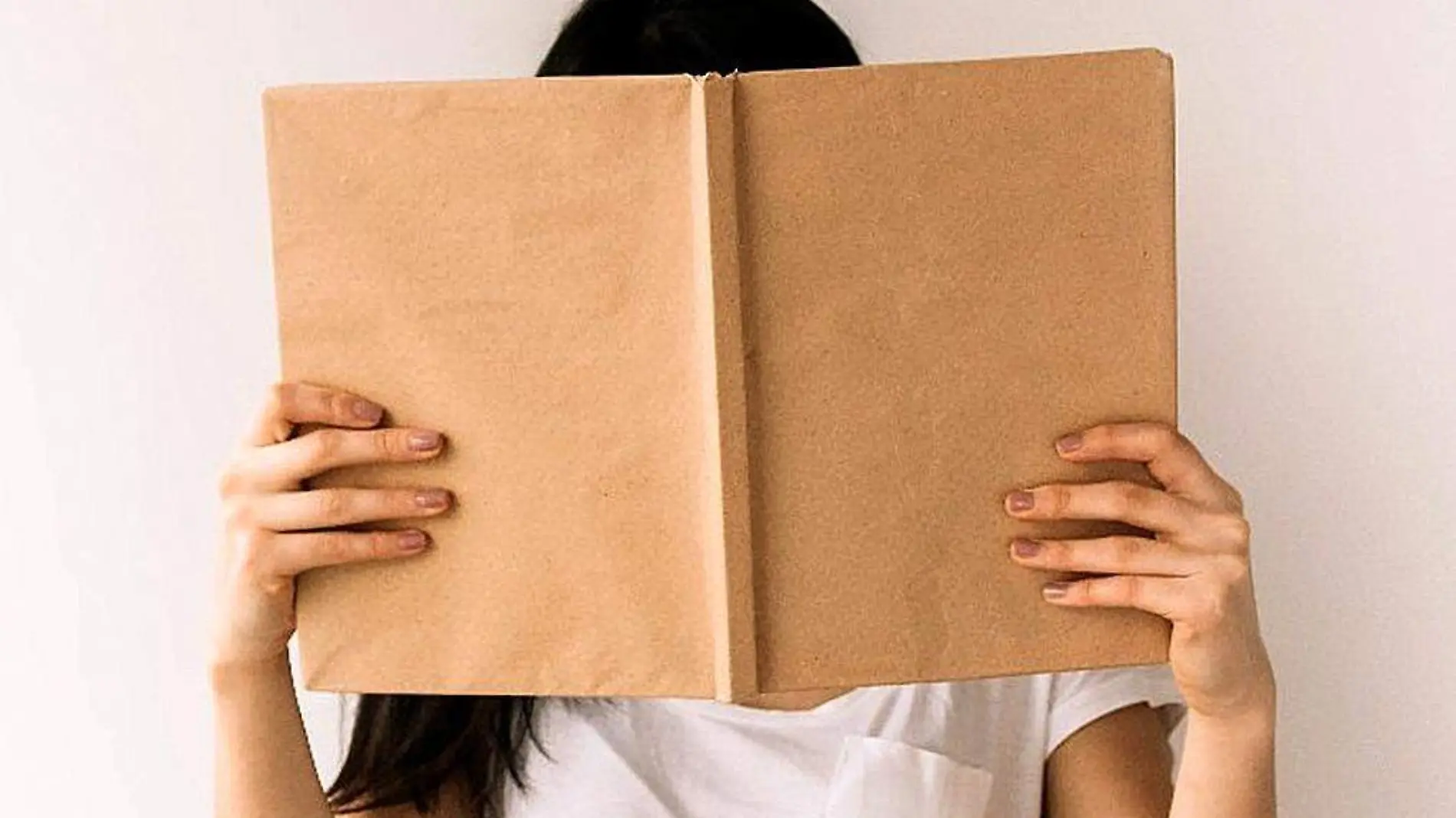 Mujer sosteniendo un libro frente a su cara